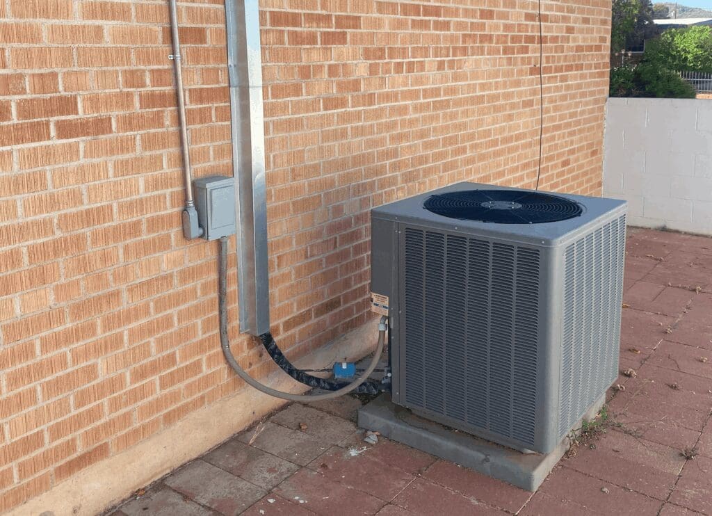 Outdoor air conditioning unit against brick wall.