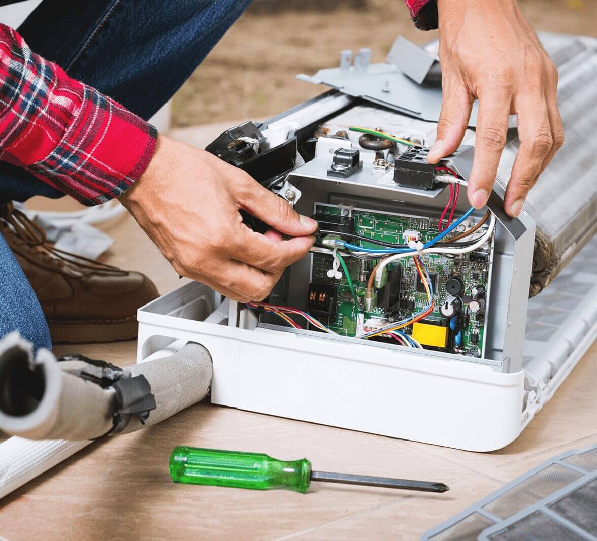 Technician repairing air conditioning unit wiring.