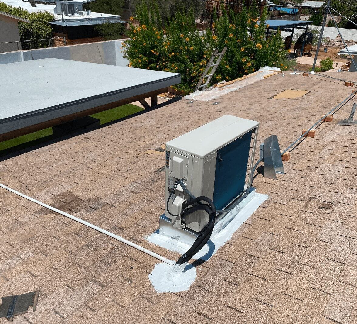 Air conditioning unit on shingle rooftop.