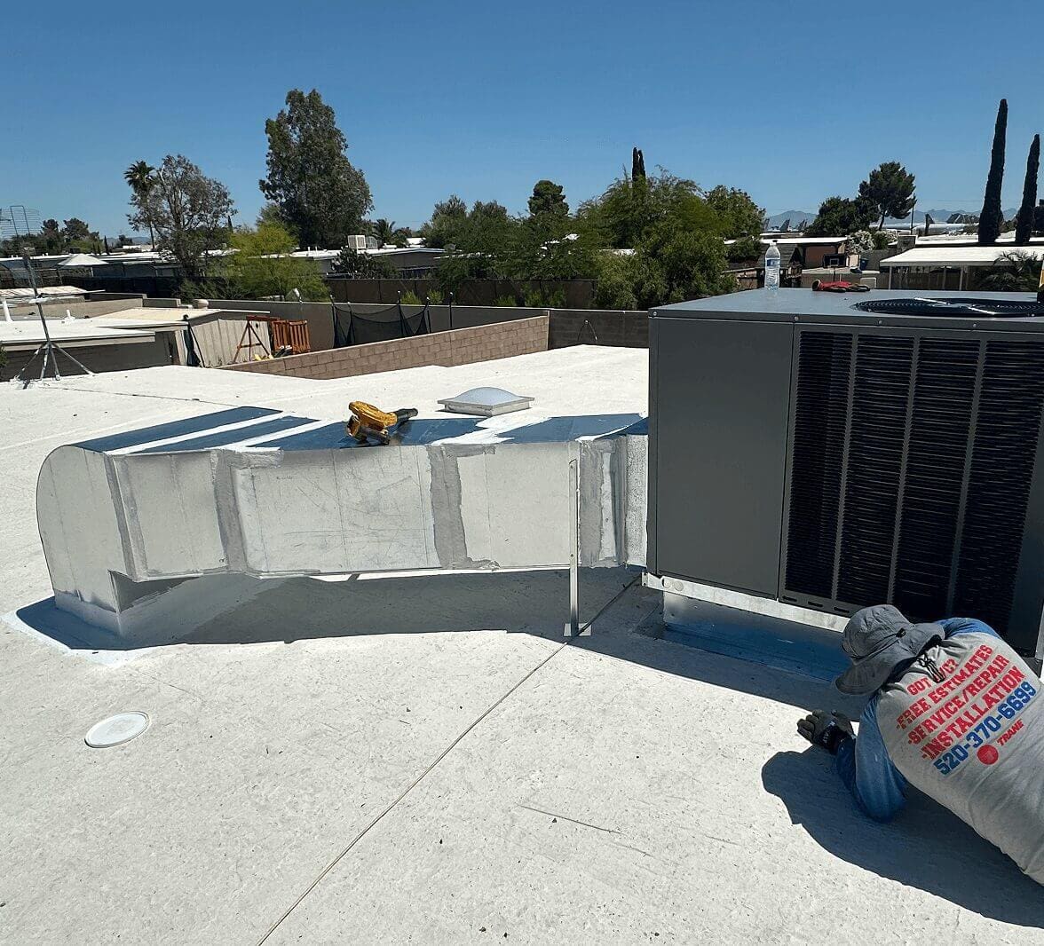 Worker installing air conditioning unit on roof.