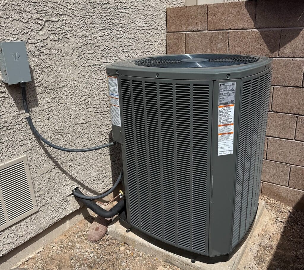 Outdoor air conditioning unit beside brick wall.