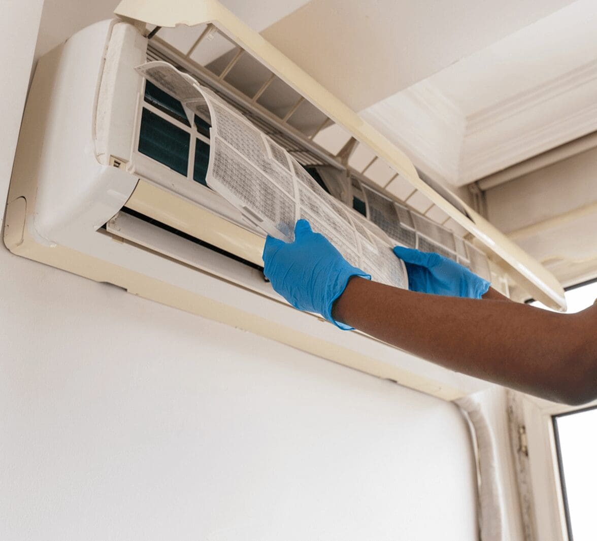 Cleaning air conditioner filter with gloved hands.