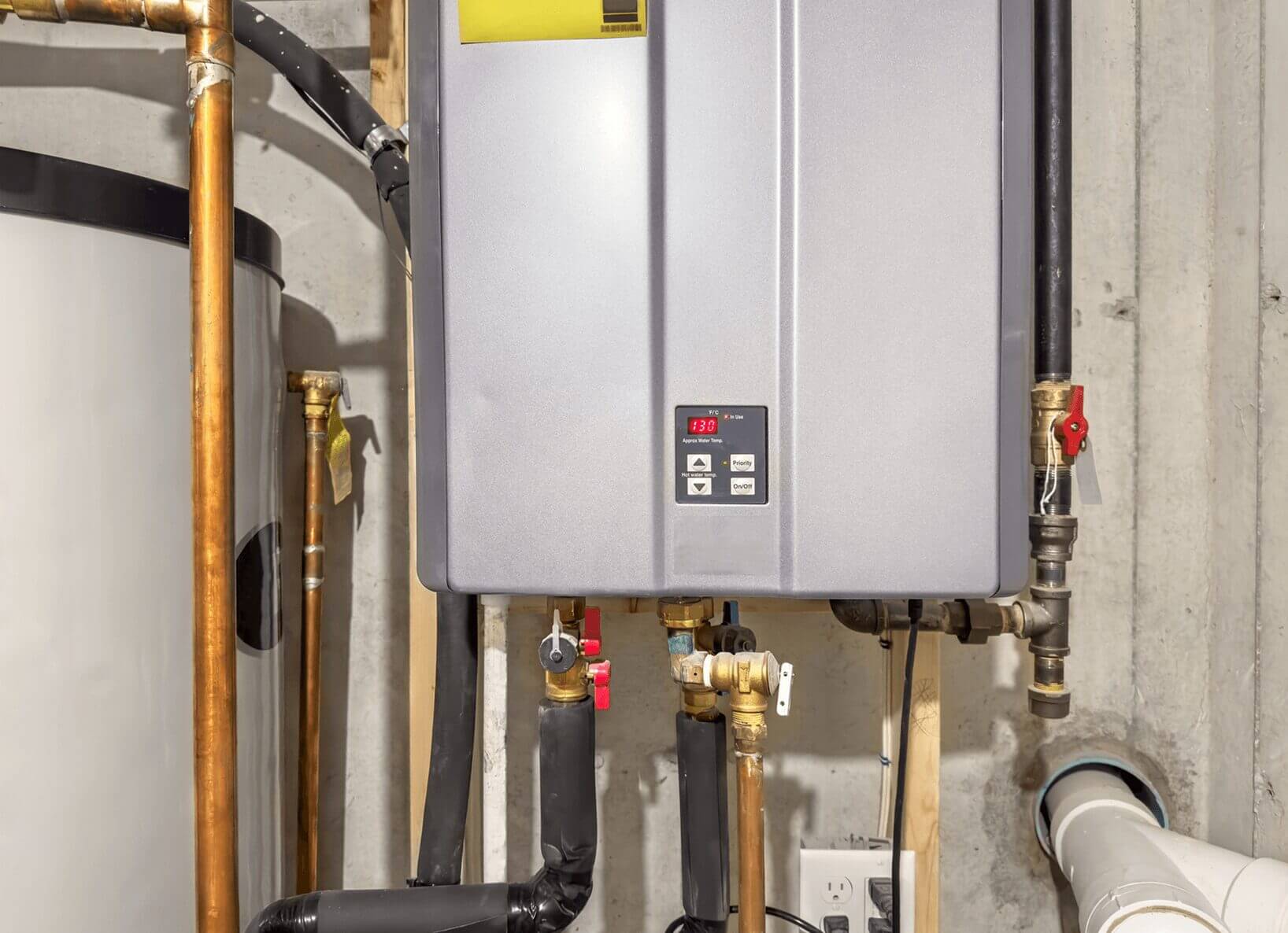 Tankless water heater with pipes in basement.