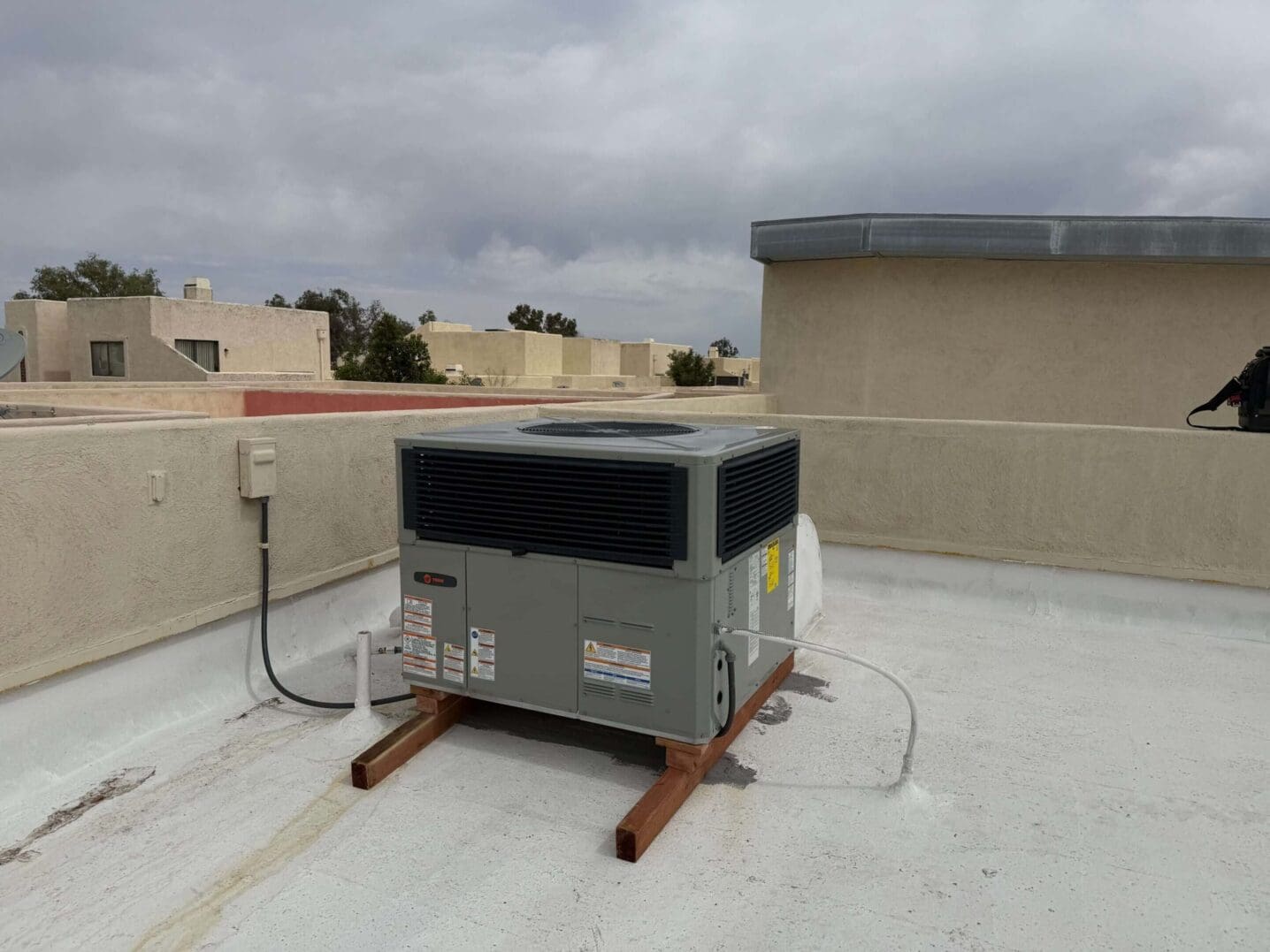 Rooftop air conditioning unit under cloudy sky.