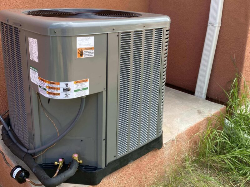 Outdoor air conditioning unit beside a building wall.