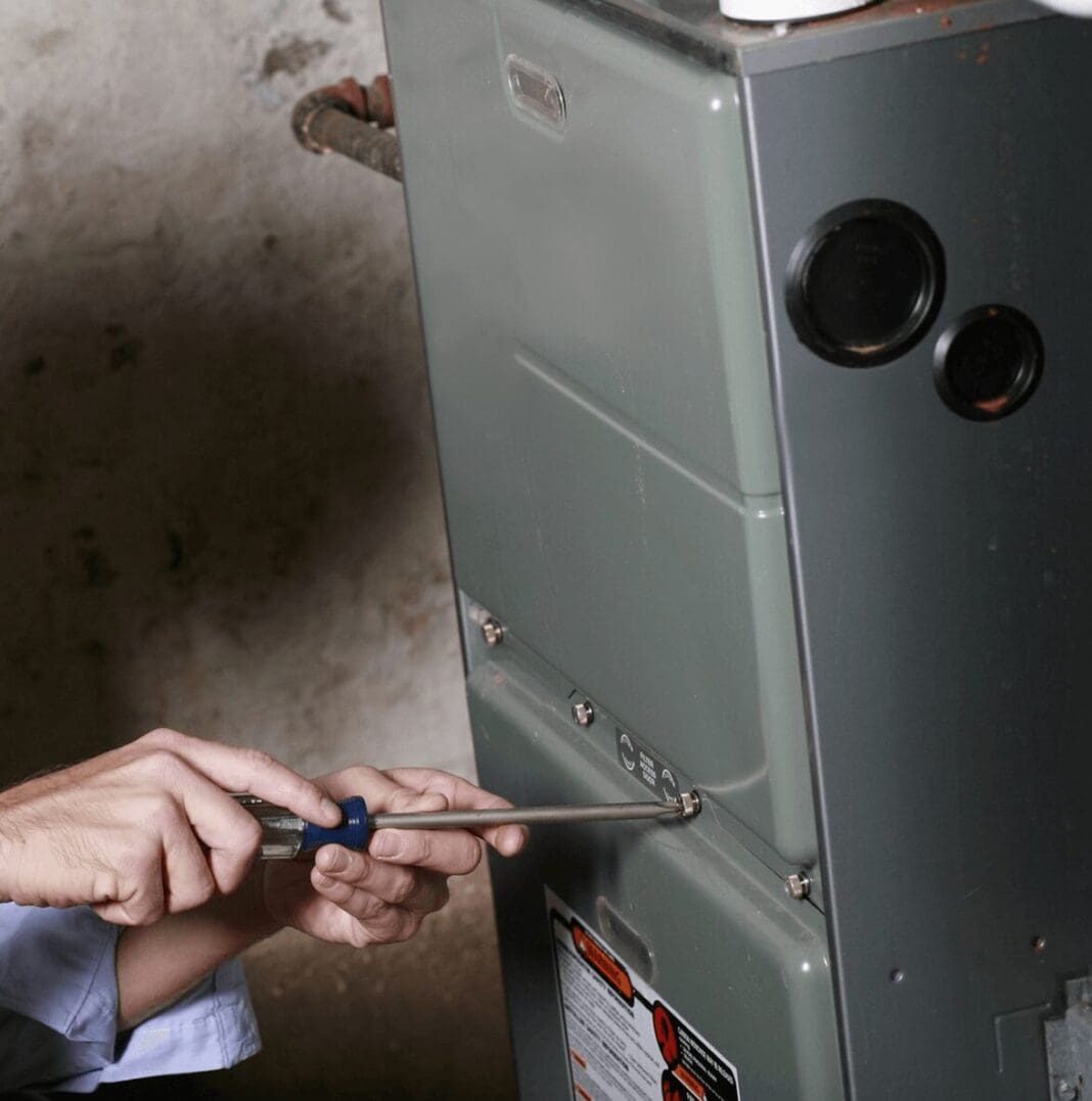Person repairing a furnace with screwdriver.
